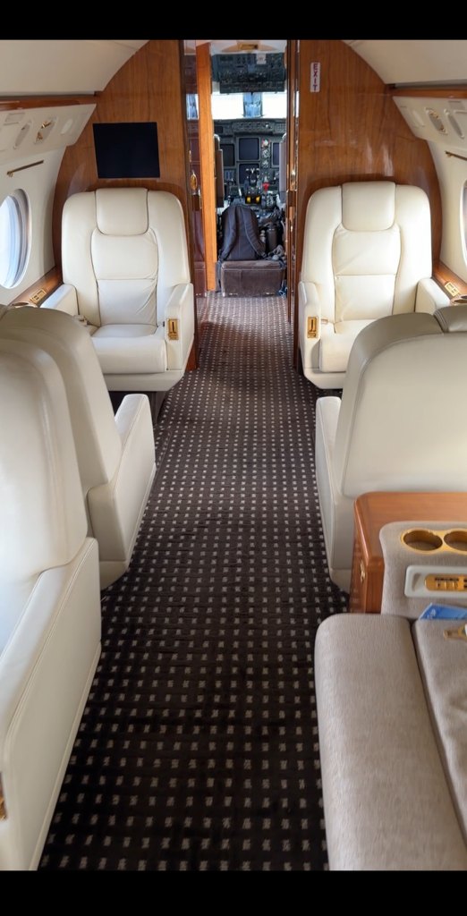 Private jet cabin interior with leather seating looking forward toward the flight deck