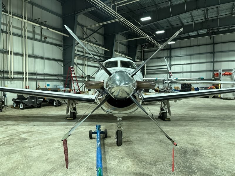 Front view of a turboprop aircraft and its propeller inside a hangar
